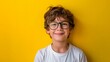 © zaa - A happy young boy in glasses smiles against a bright yellow abstract background, making for a cheerful and lively wallpaper.