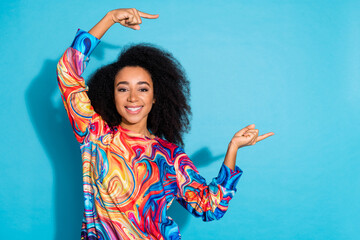 Poster - Photo portrait of beautiful curly hair woman in trendy sweatshirt index fingers empty space proposition isolated on blue color background