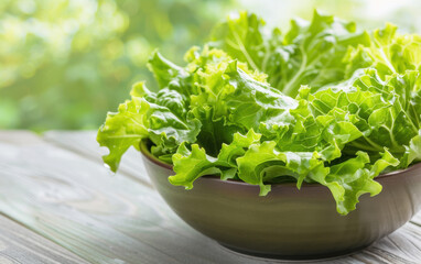 Wall Mural - Fresh green lettuce leaves in a bowl on a wooden table outdoors, sunlit background. Perfect for healthy eating and organic food concepts.