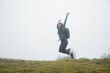 © Yoel Garay - Turista con mochila Saltando a la Aventura Desconocida en la Naturaleza Neblinosa, concepto de éxito en viajes, libertad Aventura en la Niebla,