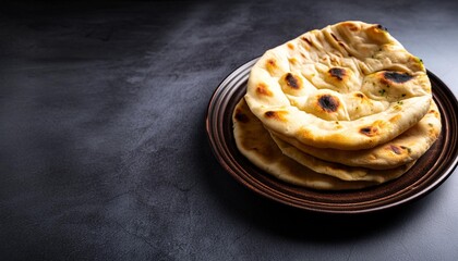 Wall Mural - fresh naan bread on plate over gray cement background several perfect naan flatbreads