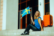 © nicoletaionescu - Happy Woman Holding Swedish Flag traveling to Sweden. Tourist going to her favorite destination celebrating its culture