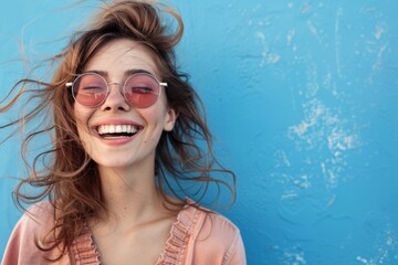 Wall Mural - Cheerful young woman in sunglasses against blue background