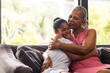© Wavebreak Media - Senior African American grandmother embraces a teenage biracial granddaughter at home