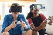 © Wavebreak Media - Happy diverse female friends wearing vr headsets and playing video games at home