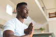 © Wavebreak Media - African american man with eyes closed and hands in prayer pose practicing yoga meditation at home
