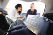 © Wavebreak Media - Two happy diverse senior female friends going on trip packing car boot with luggage, copy space