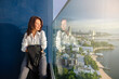 © shine - Middle-aged mature asian woman sitting hotel terrace in a sunny day, feeling good and enjoying cityscape with beach.