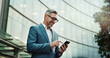 © SneakyPeakPoints/peopleimages.com - Mature, typing and city businessman smartphone, email and news update for social networking online. Technology, website search and corporate career, internet communication and digital or mobile app