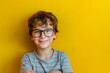 © Byk AI - A young boy wearing glasses and a striped shirt smiling brightly against a yellow background, capturing an innocent and joyful moment filled with youthful exuberance and cheerfulness.