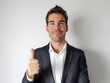 © korawik - Smiling businessman in suit gives thumbs up, expressing success and positivity