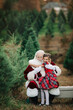 © Cavan Images - Santa hugging a girl in a plaid dress at a Christmas tree farm