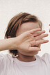 © Cavan Images - A boy's portrait on white background, hiding his face