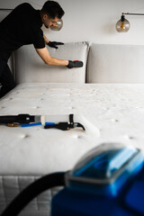 Wall Mural - Brush removing dust and stains from upholstered bed headboard and couch. Cleaner is using brush to clean the sofa pillows. Dry cleaning service.