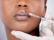 © Maass/peopleimages.com - Black woman, collagen and injection for lip filler, cosmetics and beauty on face with hyaluronic acid. Female person, mouth and syringe in studio on white background for treatment or transformation
