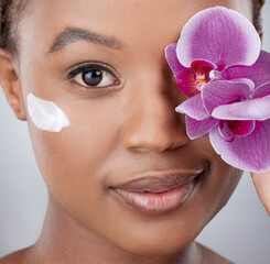 Wall Mural - Face, black woman and beauty with flower, cream and skincare on studio background. Orchid, clean and closeup for vegan lotion for female person, eco or plant based for organic cosmetic and body care