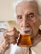 © berna_namoglu - closeup wrinkled hand of senior woman holding glass of tea