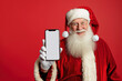 © Alexandra - Santa claus wearing eyeglasses is showing smartphone with blank screen on red background