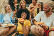 © Davide Angelini - Multicultural smiling friends eating pizza sitting outside - Cheerful young people enjoying summer vacation together - Happy life style concept with guys and girls hanging out on a sunny day