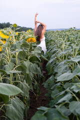 Wall Mural - Cheerful woman amidst sunflowers in field at sunset