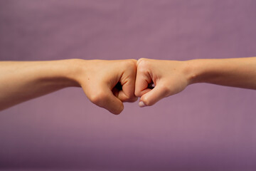 Beautiful female hand on isolated on purple background two hands fist to fist support sign language