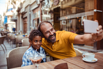 Wall Mural - Father and son taking a selfie at an outdoor cafe with ice cream