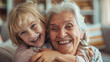 © Trendy Graphics - Happy blonde grandma and granddaughter child playing active games on home sofa. Grandmother and grandkid enjoying funny leisure on family meeting, having fun, hugging on couch