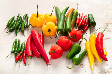 Colorful raw peppers on a light wooden background. Delicious vegetables concept.