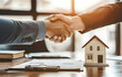 © sornram - Business handshake in office with house model and documents. Symbol of real estate, agreement, and partnership in professional setting.
