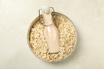 Wall Mural - Bottle of milk in bowl with oatmeal on light background, top view