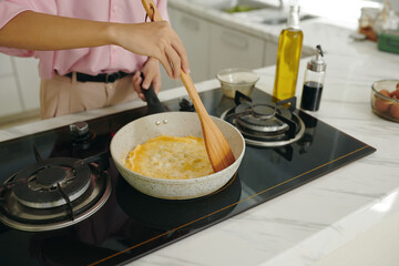 Woman making omelet on pan for breakfast in the kitchen