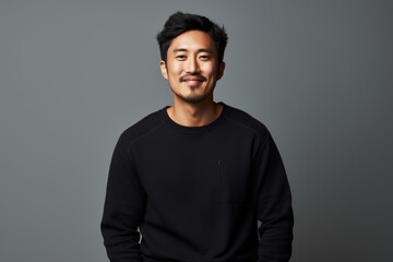 Portrait of a glad asian man in his 30s dressed in a comfy fleece pullover isolated in minimalist or empty room background