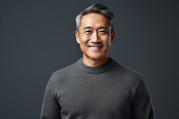 Wall Mural - Portrait of a happy asian man in his 50s wearing a cozy sweater in minimalist or empty room background