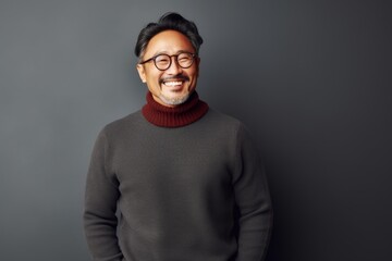 Wall Mural - Portrait of a happy asian man in his 50s wearing a cozy sweater on minimalist or empty room background