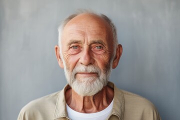 Poster - Portrait of a grinning man in his 70s wearing a simple cotton shirt isolated in minimalist or empty room background