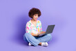 © deagreez - Full size photo of pretty young girl sit floor hold netbook wear trendy colorful outfit isolated on purple color background