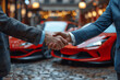 © btiger - Business handshake between car salesman and customer closing a deal at dealership with red sports cars in showroom