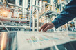 © Pajaros Volando - Engineer reviewing data charts in an industrial facility with machinery and equipment in the background.