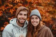 © CogniLens - Portrait of a smiling caucasian couple in their 20s sporting a comfortable hoodie in front of background of autumn leaves