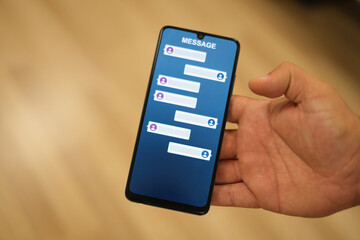 A close-up image of a hand holding a smartphone displaying a messaging app screen with blank conversation bubbles. Perfect for illustrating communication or technology themes.