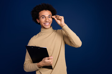 Wall Mural - Photo portrait of handsome young man hold documents cheerful dressed stylish beige garment isolated on dark blue color background