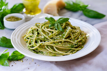 Wall Mural - tasty italian spaghetti pasta alla genovese with green pesto sauce, cheese and basil, close up