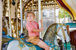 © Irina Schmidt - Happy positive preschool girl having a ride on the old vintage merry-go-round in city of St Malo France. Smiling child on a horse.