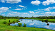 © Matthew Tighe - panoramic view of lake with meadow and forest. Clouds in blue sky