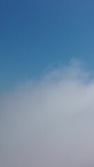 Wall Mural - aerial view. blue sky sun and fog over calm sea. the drone flies over foggy and fluffy clouds. abstr