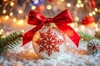 © bramthestocker - White sparkling Christmas tree toy with a red bow and a red snowflake on a background of snow