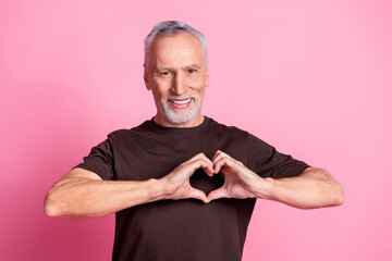 Sticker - Portrait of appreciative man with white gray beard dressed brown t-shirt showing heart symbol on chest isolated on pink color background