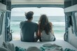 © GHArtwork - Rear of young couple sitting and taking a beach view on mattress inside of camper van