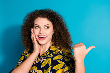 Wall Mural - Photo of charming excited woman wear print shirt pointing thumb empty space isolated blue color background