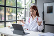 © Wasana - A woman in a white lab coat is talking on a tablet computer